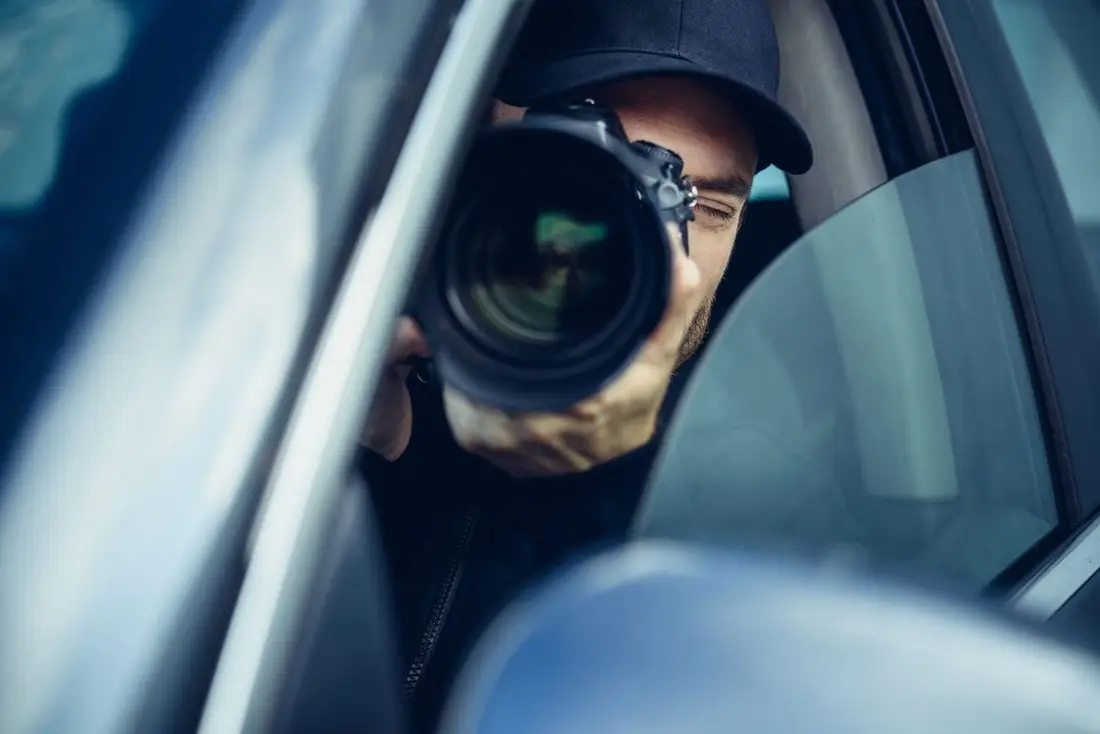 Investigador privado fotografiando desde un auto